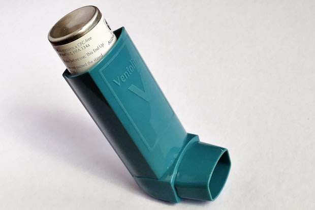 An asthma inhaler on a plain background