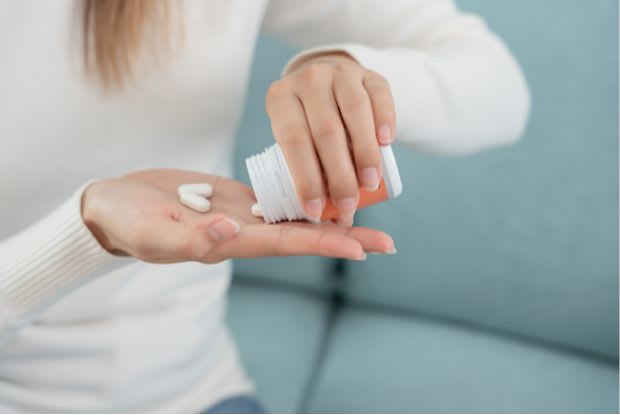 a woman taking medication tablets