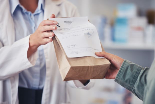 A pharmacist giving a patient their medication in a bag