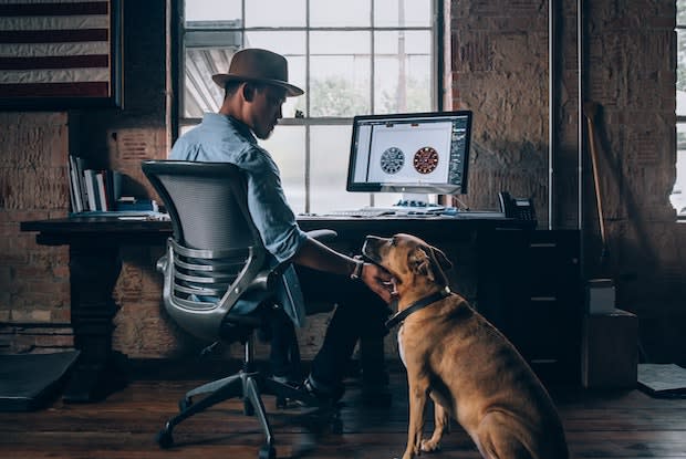 a man at his work desk, petting a dog