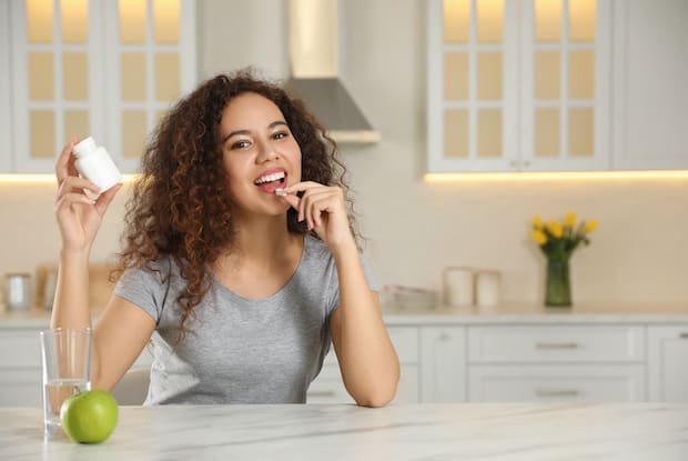 a woman taking a pill while smiling