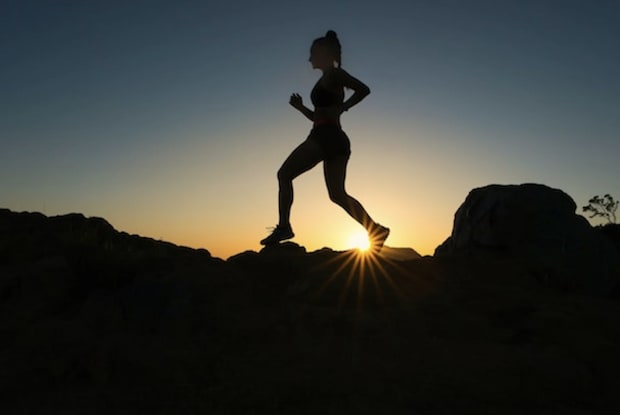 a silhouette of a woman jogging at sunset