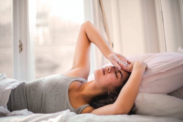 A woman lying in bed, holding her head