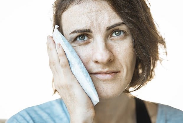 a woman applying an ice pack to her face