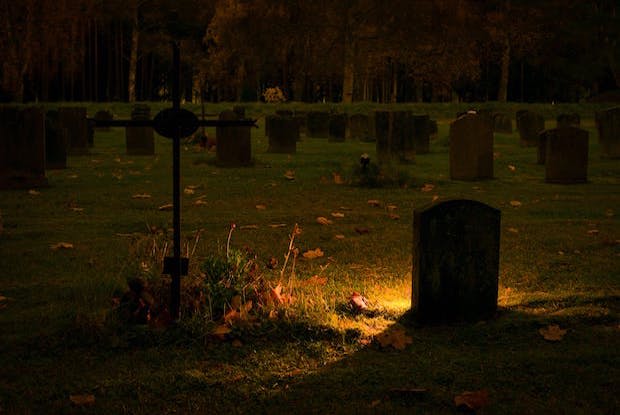 A grave in a graveyard lit up at night