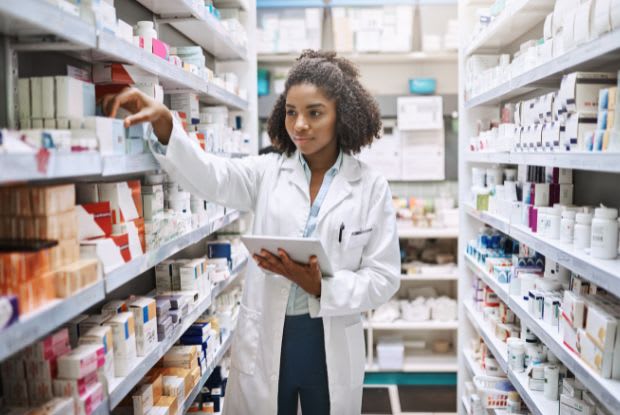 a pharmacist looking at medication on shelf