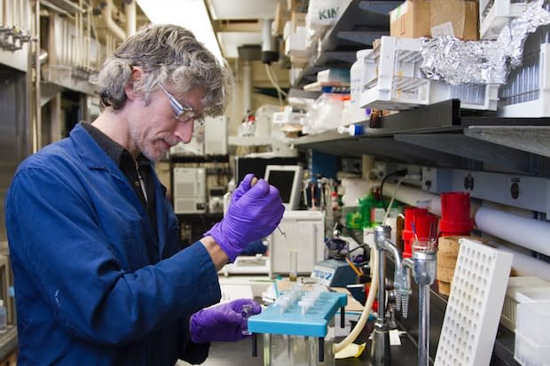 a scientist putting samples of fluids into test tubes