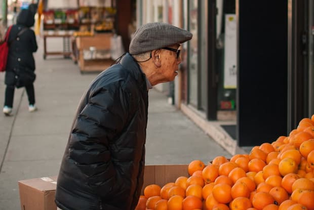 an older man buying oranges at a market