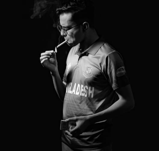 a grayscale photo of a man lighting a cigarette