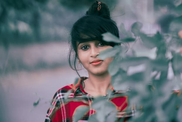 a woman standing in front a bush