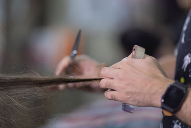 a hair stylist cutting someone’s hair