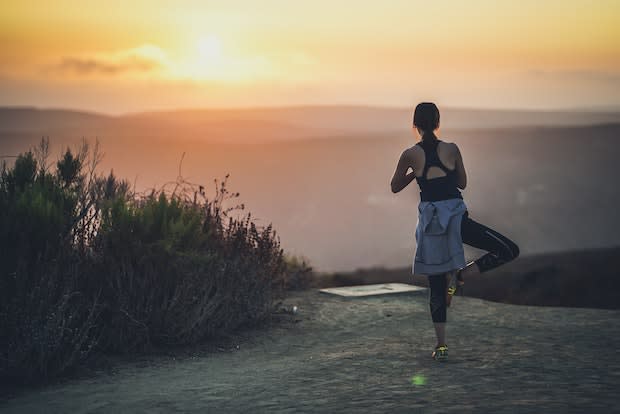 a woman doing a yoga pose during a sunset