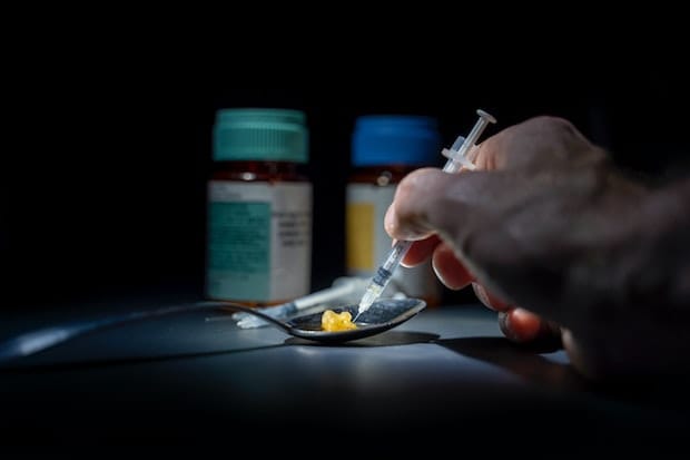 a person filling a needle with intravenous drugs