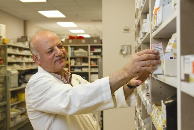 A pharmacist reaches for medication from a shelf