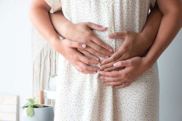 a pregnant woman embraced by her significant other