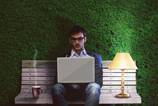 a man on a bench using his laptop