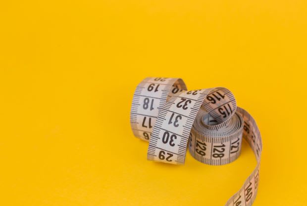 a curled-up measuring tape on a yellow background