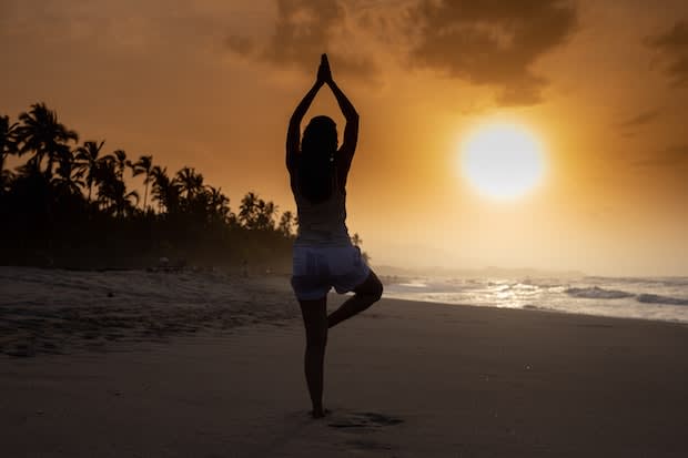 a woman performing yoga on a beach