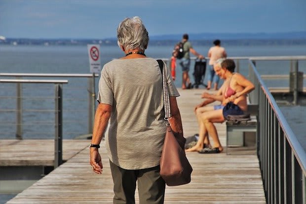 an older person walking on a boardwalk