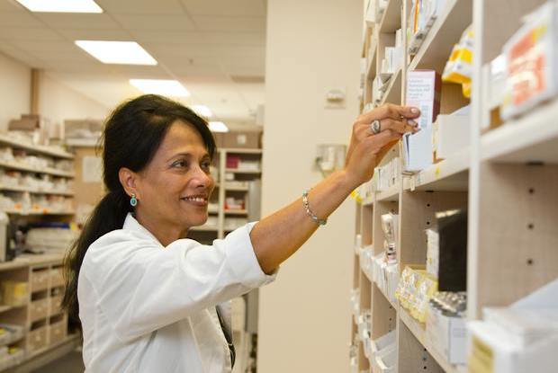 a pharmacist reaching for medications on a shelf