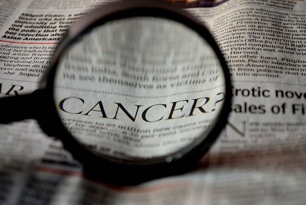 the word “cancer” magnified on a newspaper