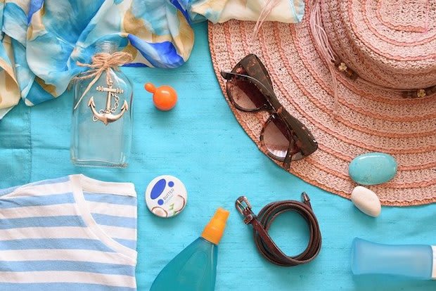 a blanket with sunglasses, a hat, and sunscreen on top