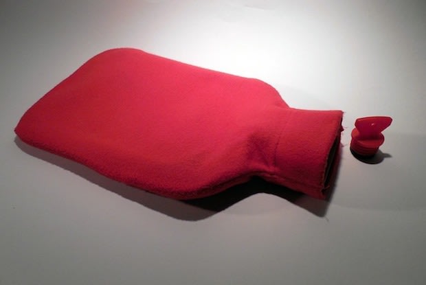 A red hot water bottle on a plain background