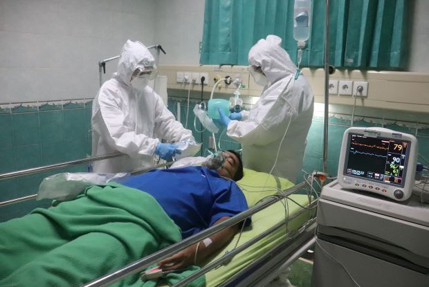 a patient on a hospital bed being worked on by masked doctors