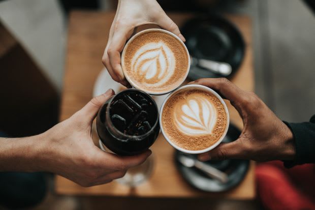 three people holding up coffee beverages