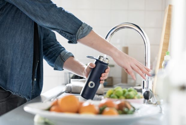 a person filling up a water bottle