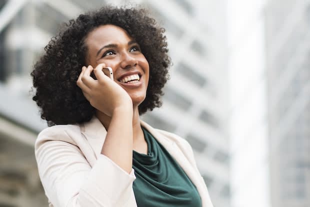 woman using telephone standing near building