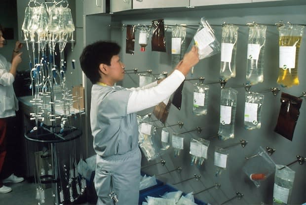 a woman hanging up different bags of chemotherapy