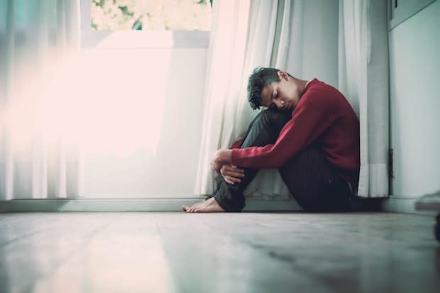 a man looking sad sitting in a corner