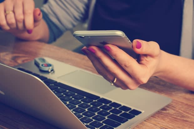 a person holding a phone and looking at a computer