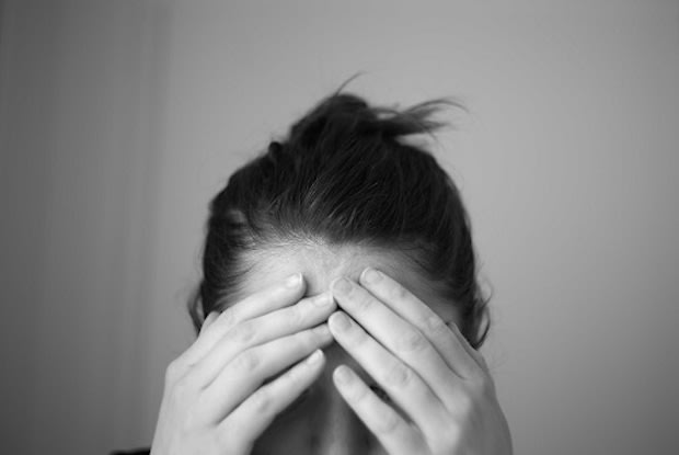 A black and white photo of a man holding his forehead