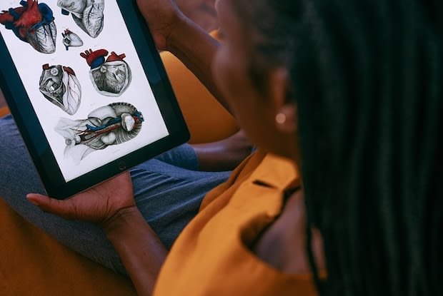 woman holding handheld tablet with anatomical diagram of heart