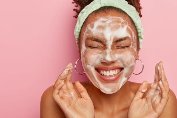 a smiling woman completing a skincare routine