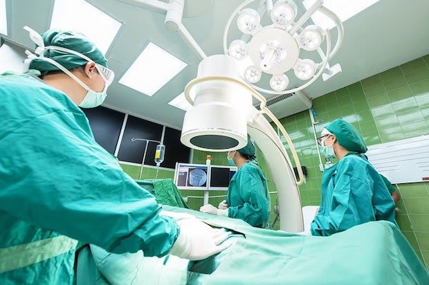 a surgery suite with a patient surrounded by doctors