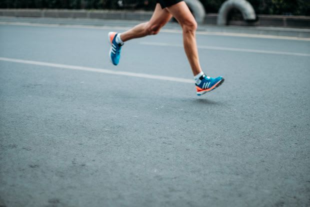 a person in blue shoes running on the road