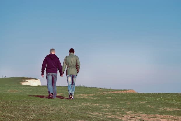 a couple walking hand in hand on a cliff