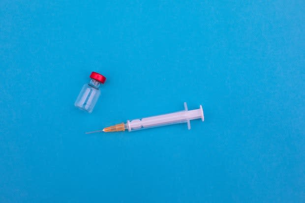 a vial and a needle on a blue background