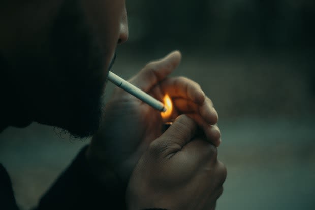 A man lighting up a cigarette