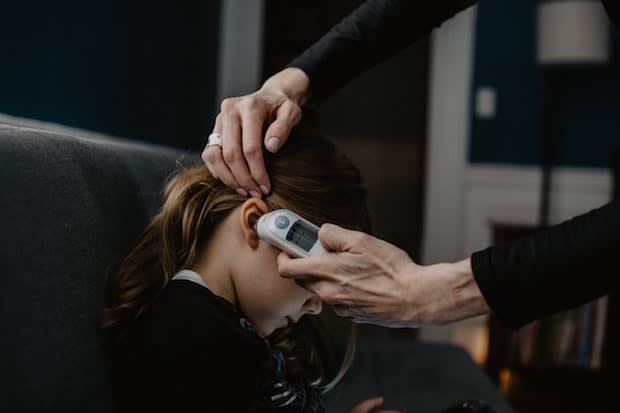 a young girl getting her temperature taken