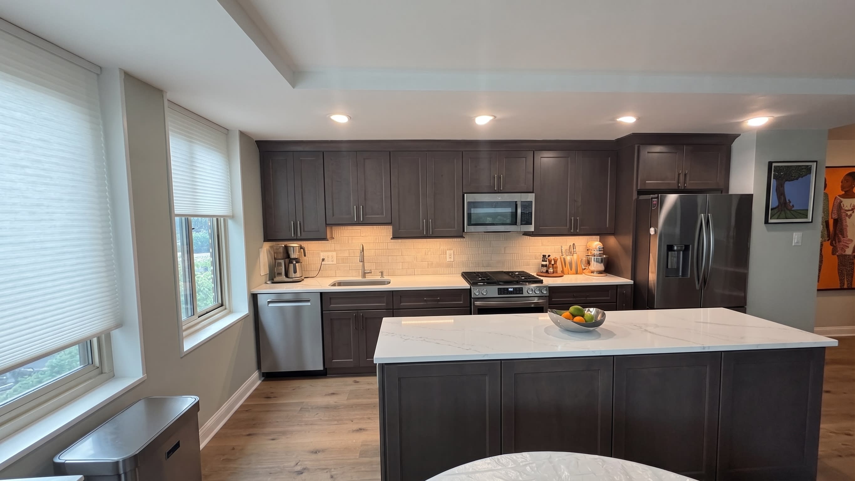 Charcoal gray kitchen island with quartz waterfall countertop and gold hardware