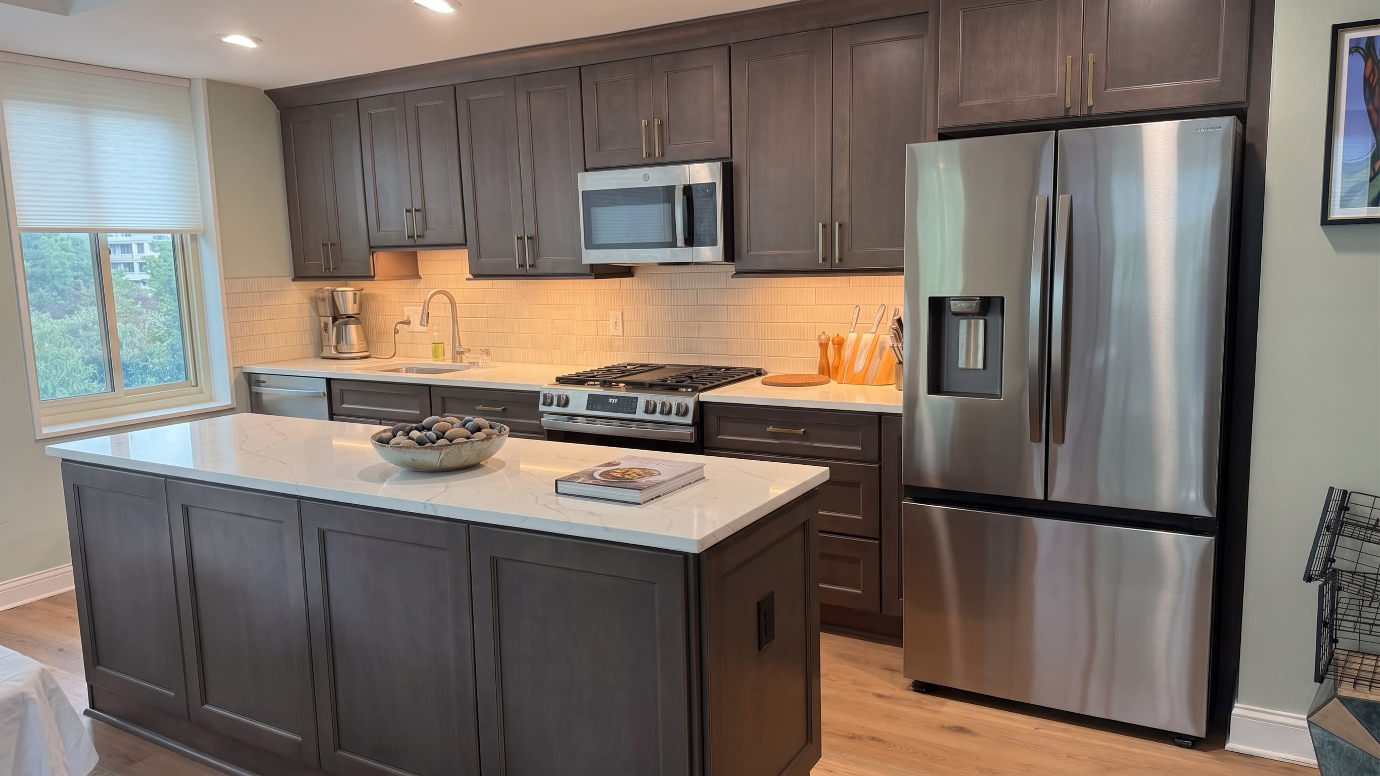 Charcoal gray kitchen island with quartz waterfall countertop and gold hardware