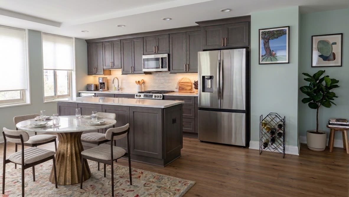 Charcoal gray kitchen island with quartz waterfall countertop and gold hardware