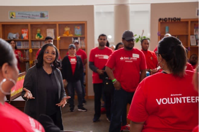 African american woman talking to a diverse group of Santander Consumer employees in red volunteer shirts