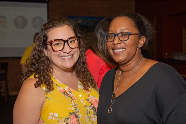 A white woman and african american woman both wearing glasses and smiling