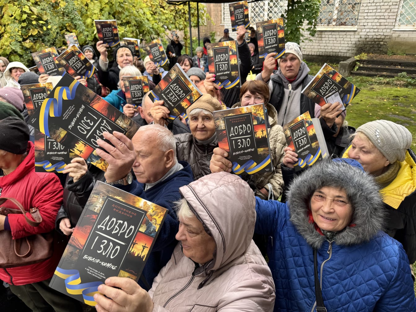 Crowd of Ukrainian villagers holding up copies of the Good and Evil book, 'Добро і Зло', outdoors