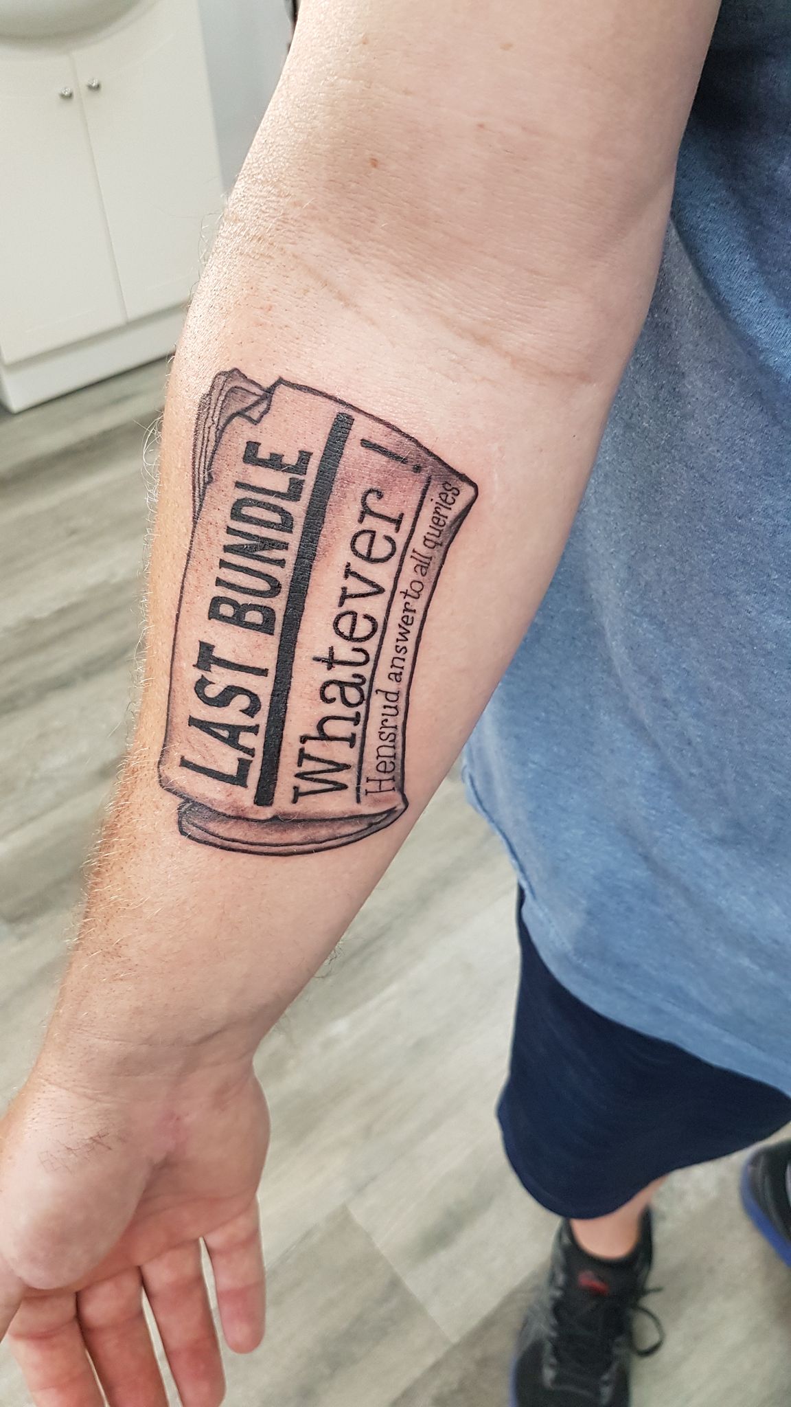 Black and white upper arm script tattoo